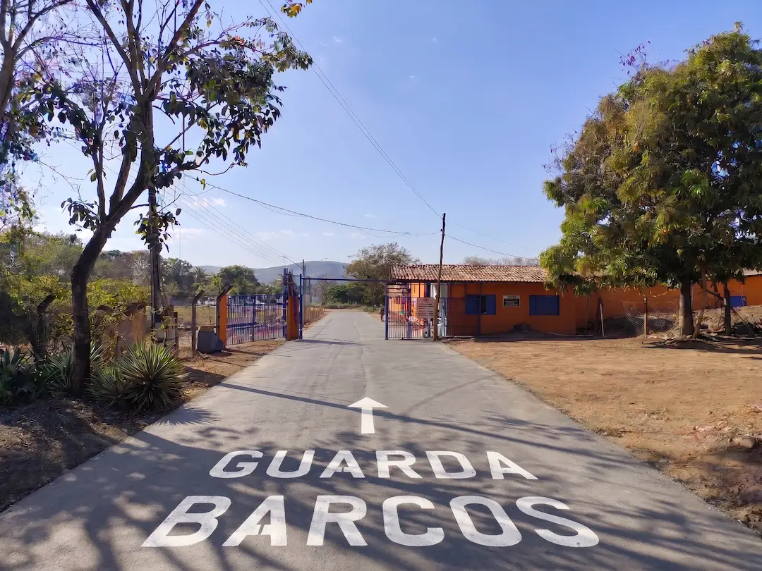 Entrada do Guarda Barcos Ypê em Caldas Novas, com acesso asfaltado até o portão e sinalização no chão